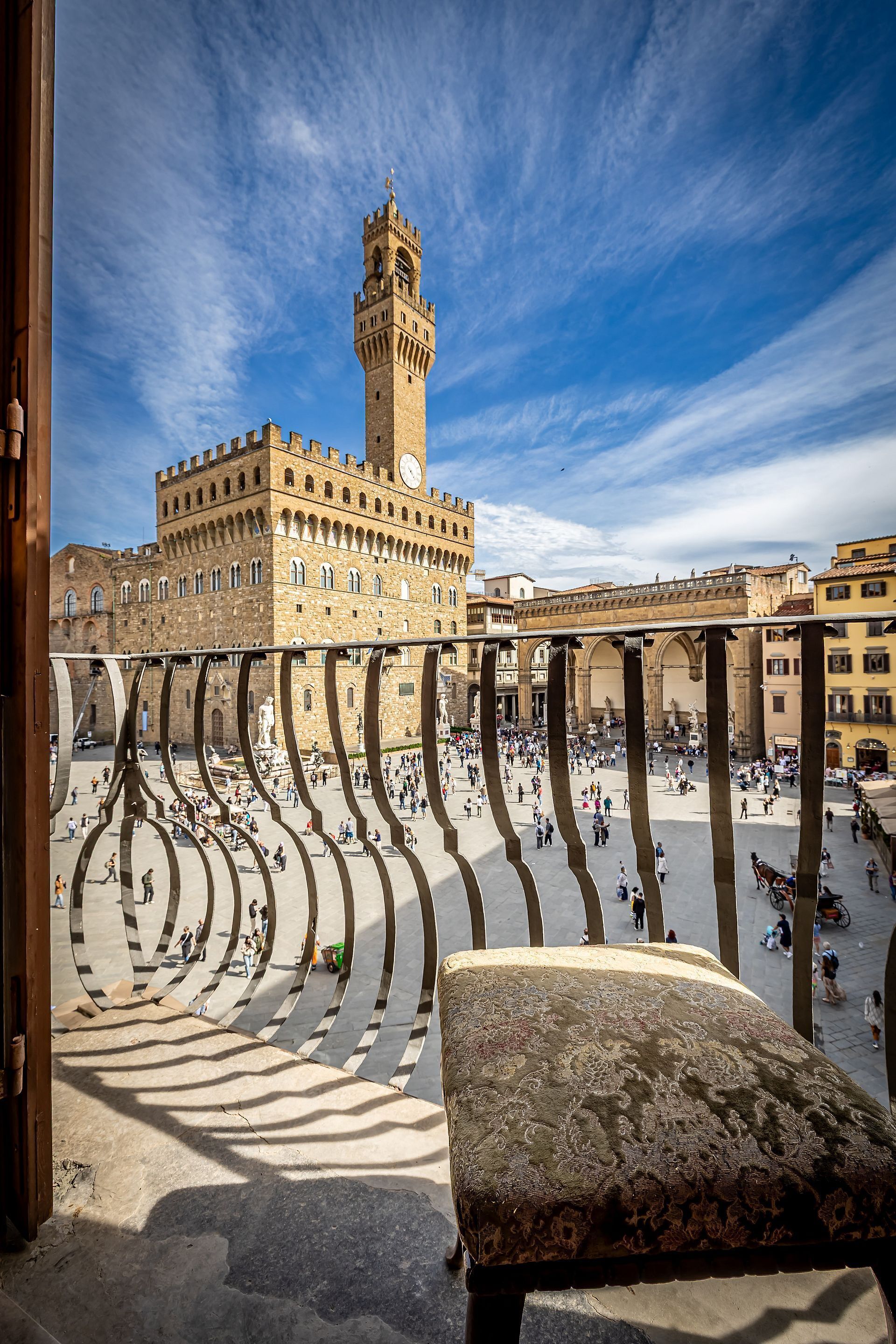 A courtyard with a tower, stone benches, and a clear sky.