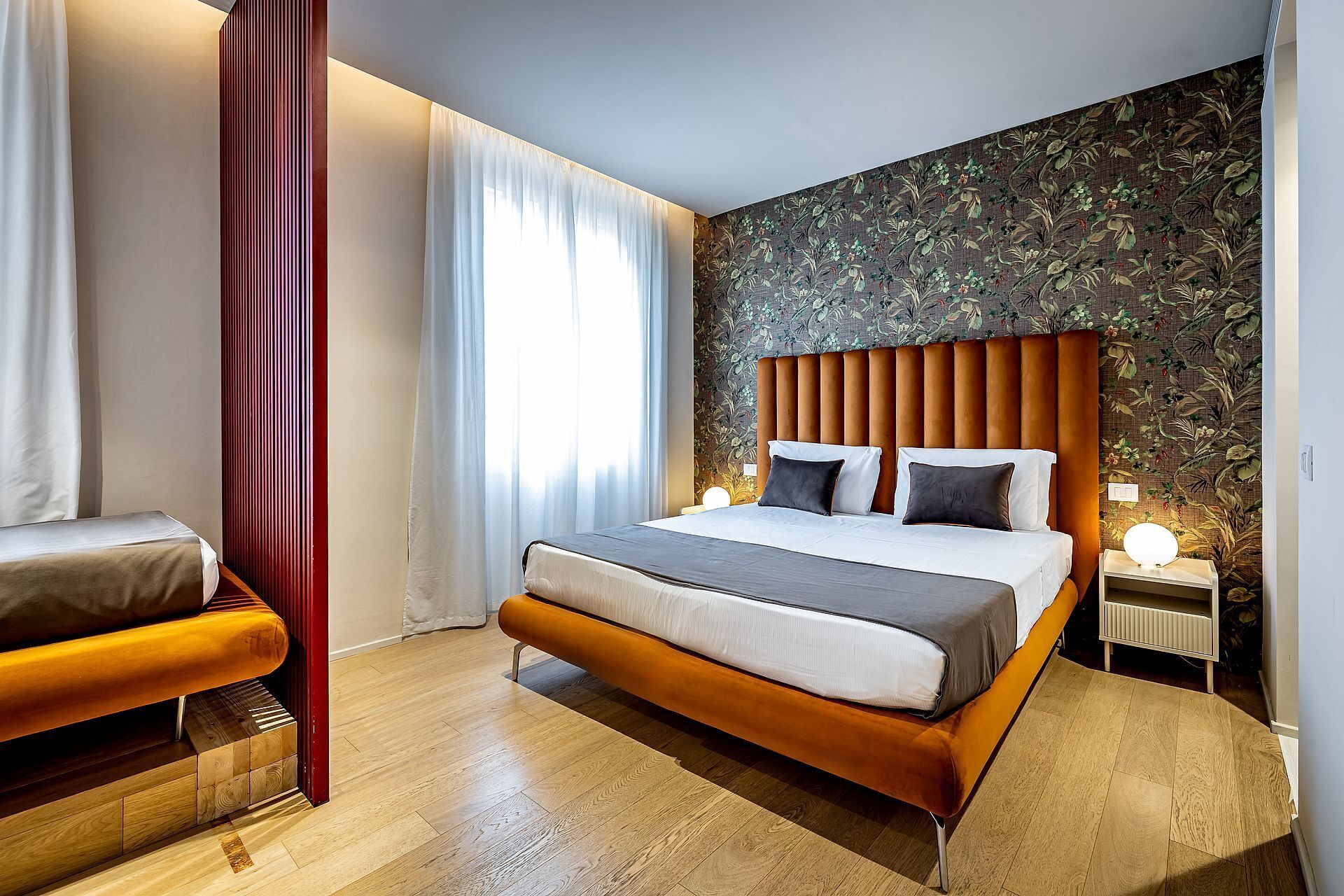 Una moderna camera d'albergo con un letto grande, una panca di legno e carta da parati decorata.