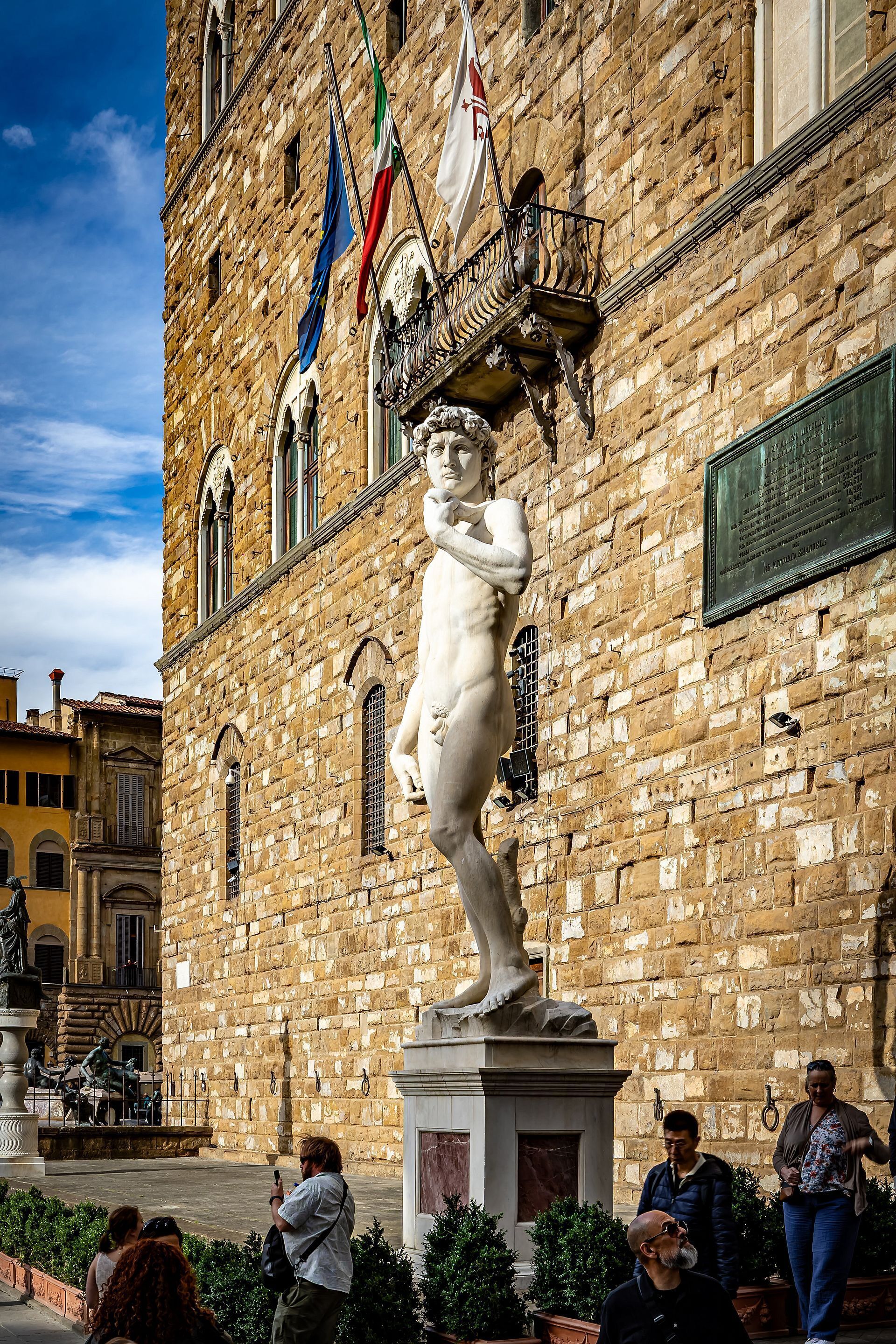 Ein historisches Gebäude mit einer Statue, Flaggen und einer Gedenktafel.