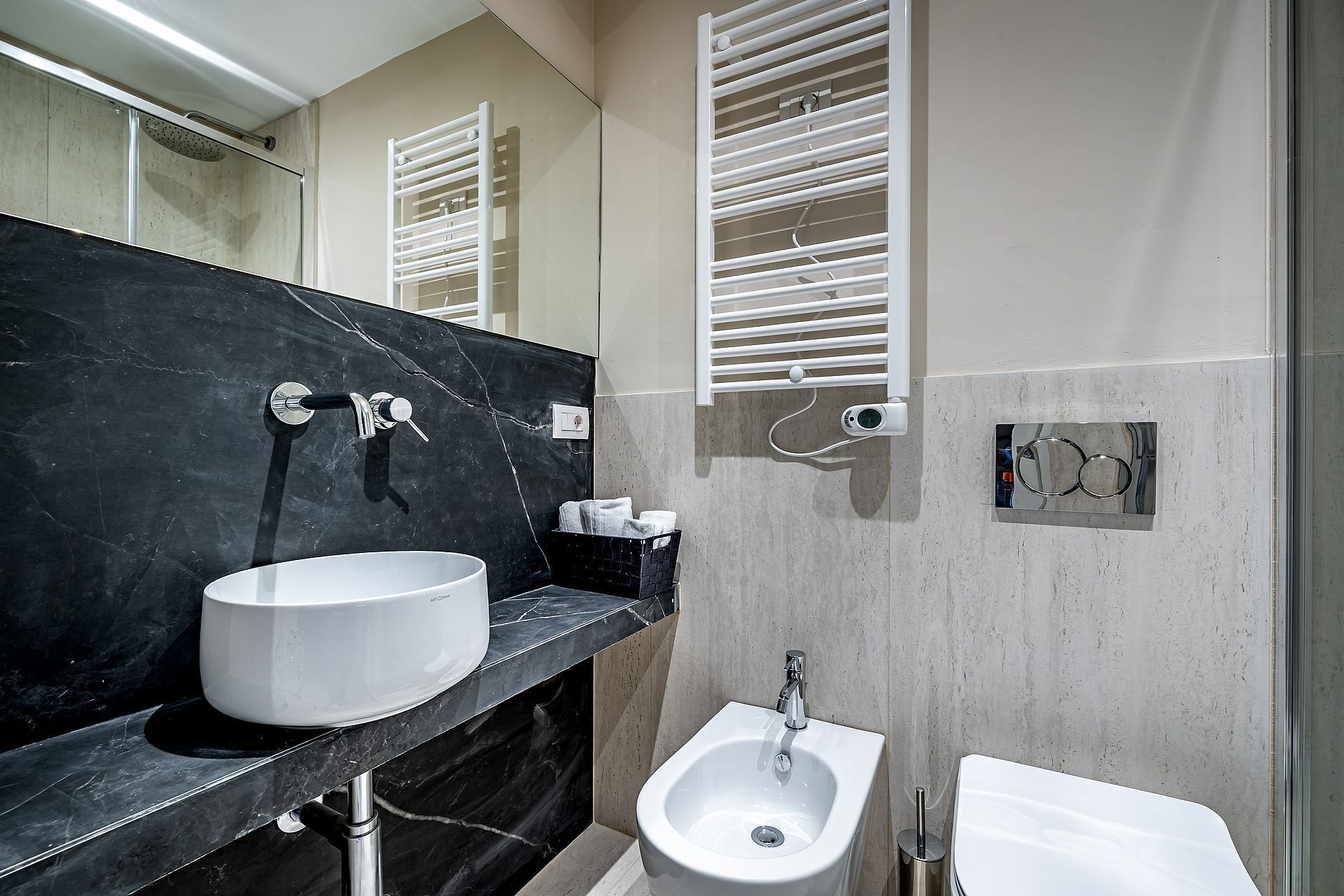 A modern bathroom with a large white sink, a bidet, and a mirror.