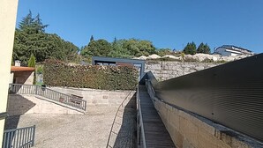 A staircase leading to a building with a stone wall and a metal railing.