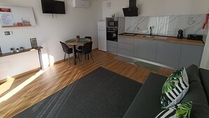A compact kitchen with a dining area, a flat-screen TV, and a built-in oven.