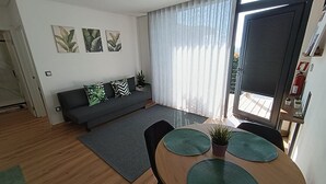 A modern living room with a sofa, dining table, and artwork on the wall.