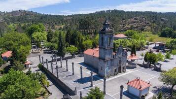 Une église dotée d’un clocher, entourée d’arbres et située dans un paysage vallonné.
