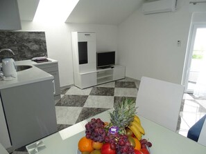 A modern kitchen with a dining area, a TV, and a fruit bowl. - Holiday home Viktoria with pool by Interhome (Rovanjska)