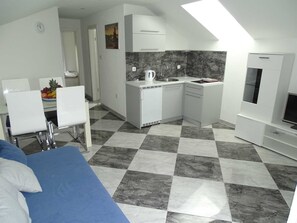 Ein kompaktes, modernes Apartment mit Küchenzeile, Essbereich und Wohnbereich.