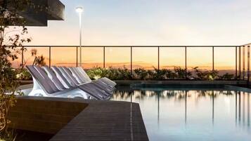 Una piscina al aire libre, sillones reclinables de piscina