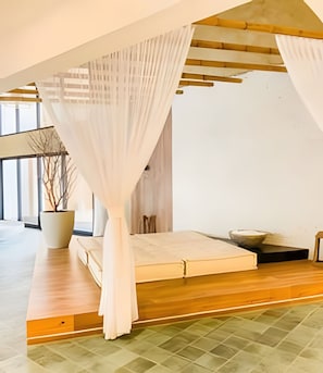 A modern bedroom with a bed, a large potted plant, and a view of the outdoors. - ID Vida Urbana  (Goiânia)