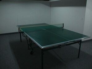 Ein Tischtennistisch in einem Raum mit Teppichboden und schlichten Wänden.