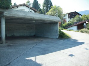 Eine Parkgarage aus Beton mit flachem Dach, umgeben von Wohngebäuden und Grünflächen.