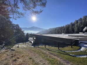 A modern building with a flat roof, surrounded by a snowy landscape and a forested area. - Alp Resort Ski In/Ski Out, (Laax Murschetg), by Interhome (Laax)