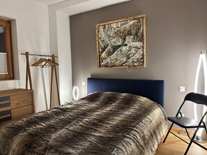 A bedroom with a bed, a wooden dresser, a chair, a coat rack, and a painting on the wall. - Alp Resort Ski In/Ski Out, (Laax Murschetg), by Interhome (Laax)