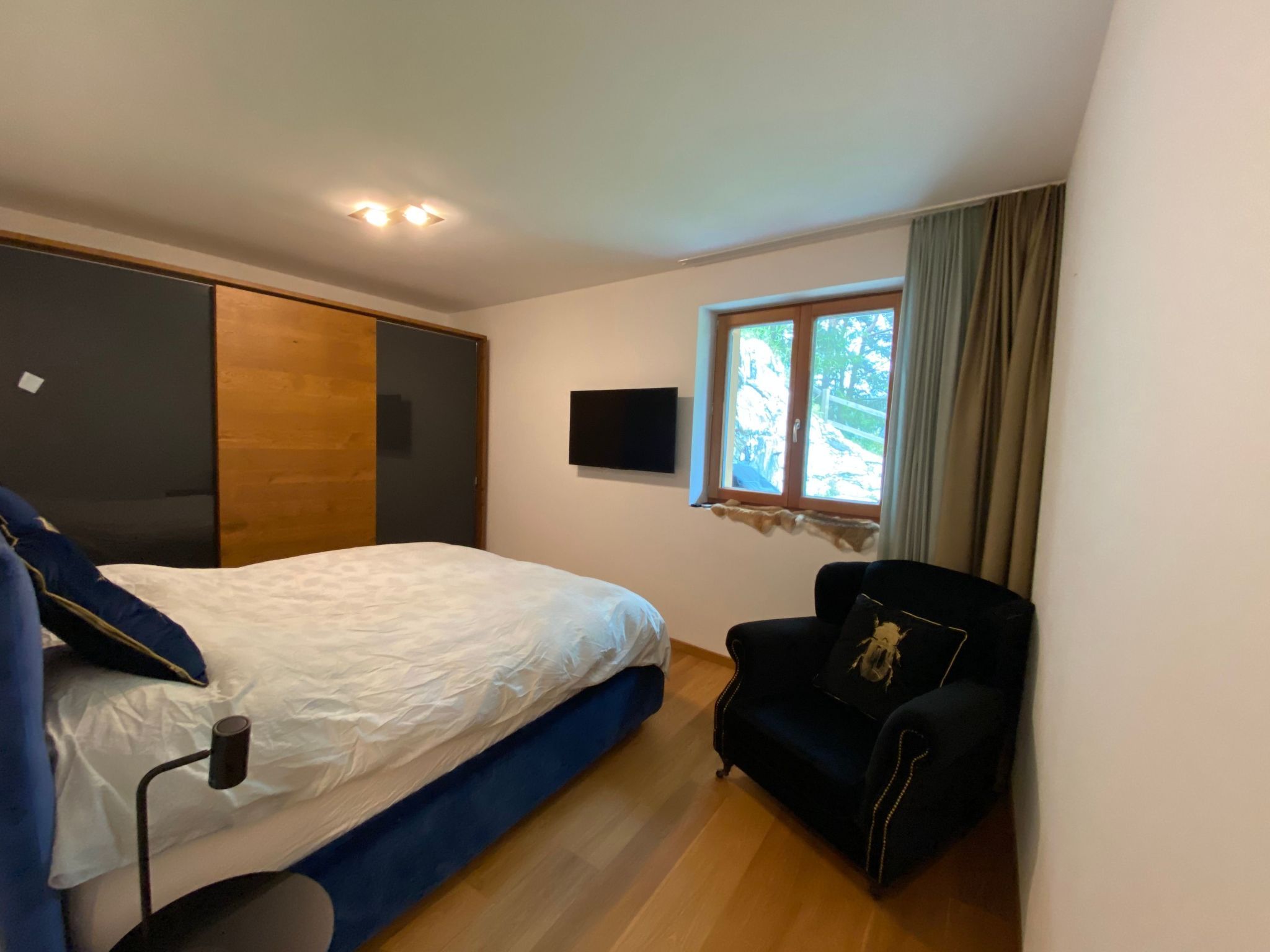 Ein Schlafzimmer mit einem Bett, einem Sessel, einem Fernseher und einem Fenster.