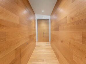 A hallway with wooden panel walls and a wooden floor leading to a door. - Alp Resort Ski In/Ski Out, (Laax Murschetg), by Interhome (Laax)