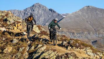 Two mountain bikers on a rocky trail with mountains in the background.
