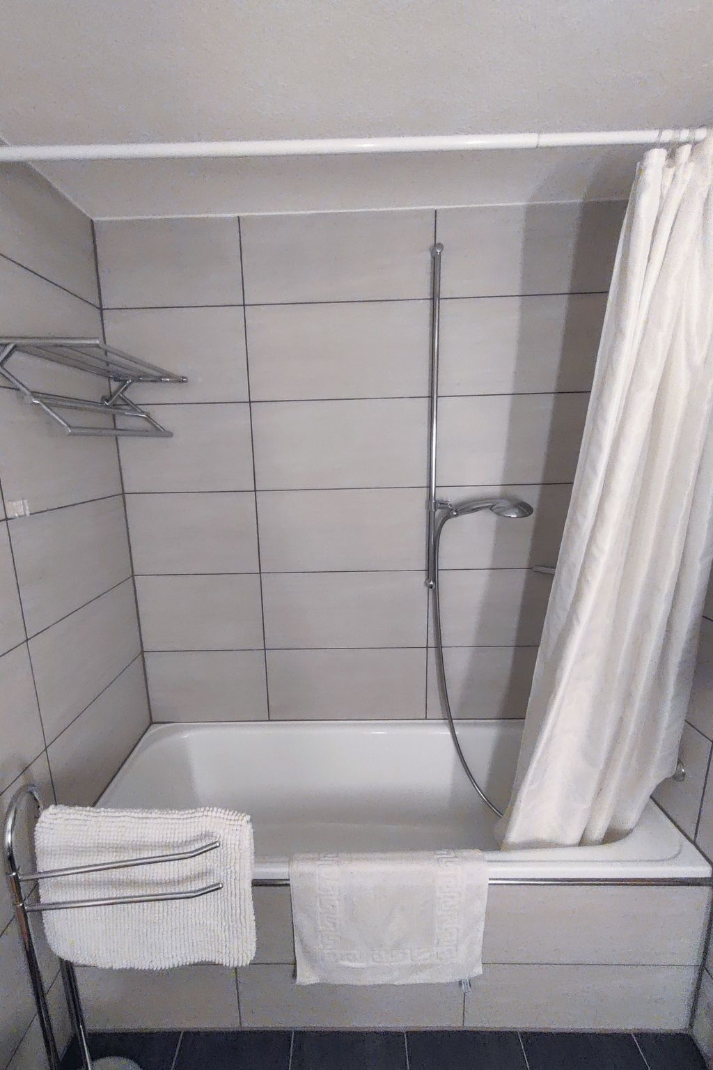 Een badkamer met een bad, een douche en een handdoekrek.