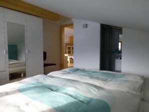 Un dormitori amb un llit, un armari i una porta que dona a una altra habitació.