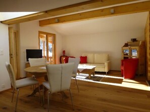A room with a dining table, chairs, a sofa, and a television. - Casa Ual / Capaul, (Laax Dorf), 332 by Interhome (Laax)