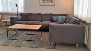 Una sala de estar con un sofá gris, una mesa de centro de madera y un tapete estampado.
