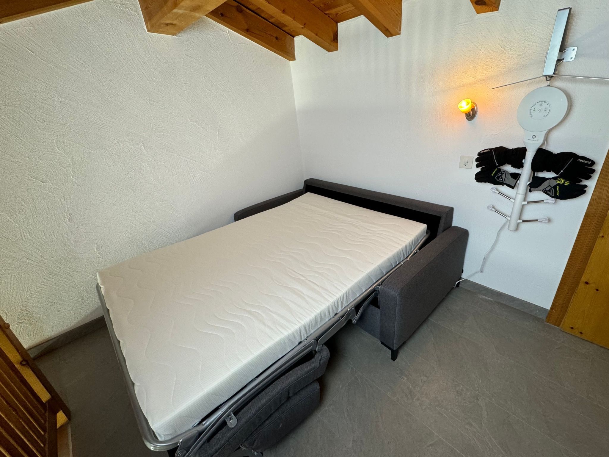 Uma cama compacta com colchão e uma gaveta deslizante embaixo.