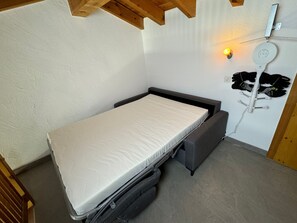 Una cama compacta con colchón y un cajón extraíble debajo.