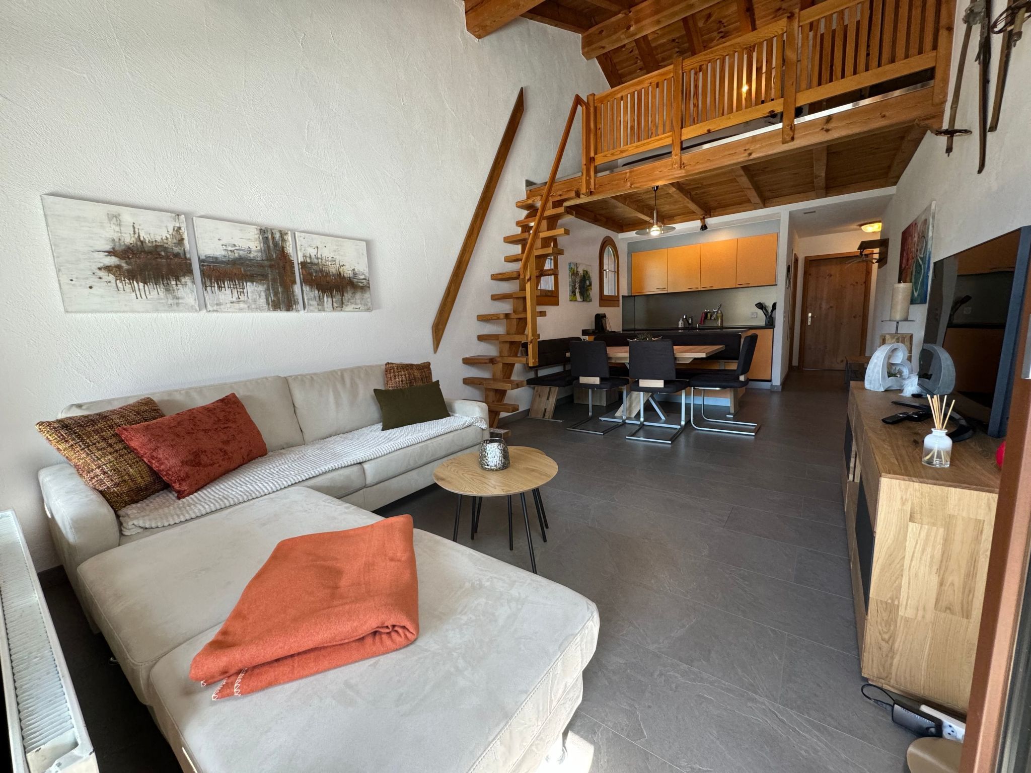 En hyggelig opholdsstue med sofa, sofabord og trappe til et loft.