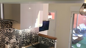 Una cocina con salpicadero estampado, lavavajillas integrado y ventana con vista a un balcón.
