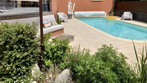 Piscina con sillones de descanso, un sofá y letrero de bar.