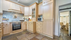 A kitchen with wooden cabinets, a microwave, an oven, and a tiled backsplash. - 7 Grade II Listed Cosy Cottage Free Parking (Ambleside)