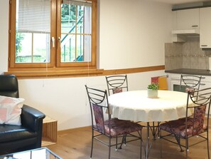Ein Essbereich mit einem runden Tisch, vier Stühlen und einem Fenster mit Blick ins Grüne.
