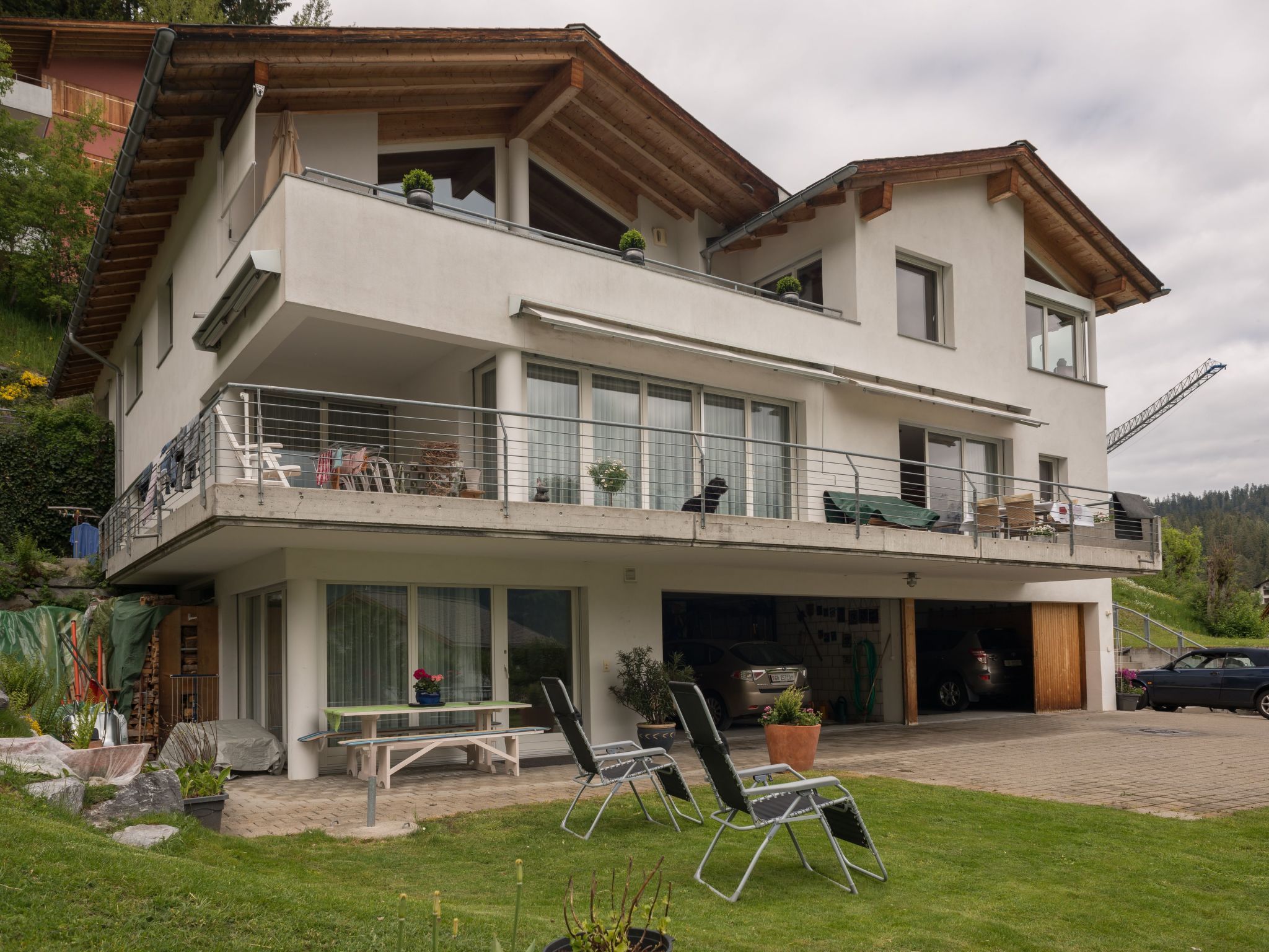 A two-story residential building with a balcony, a garage, and outdoor seating.