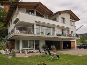 Un edificio residencial de dos pisos con balcón, garaje y zona de estar al aire libre.