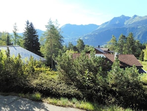 Ein Wohngebiet mit Häusern, umgeben von dichter Vegetation und Bergen im Hintergrund.