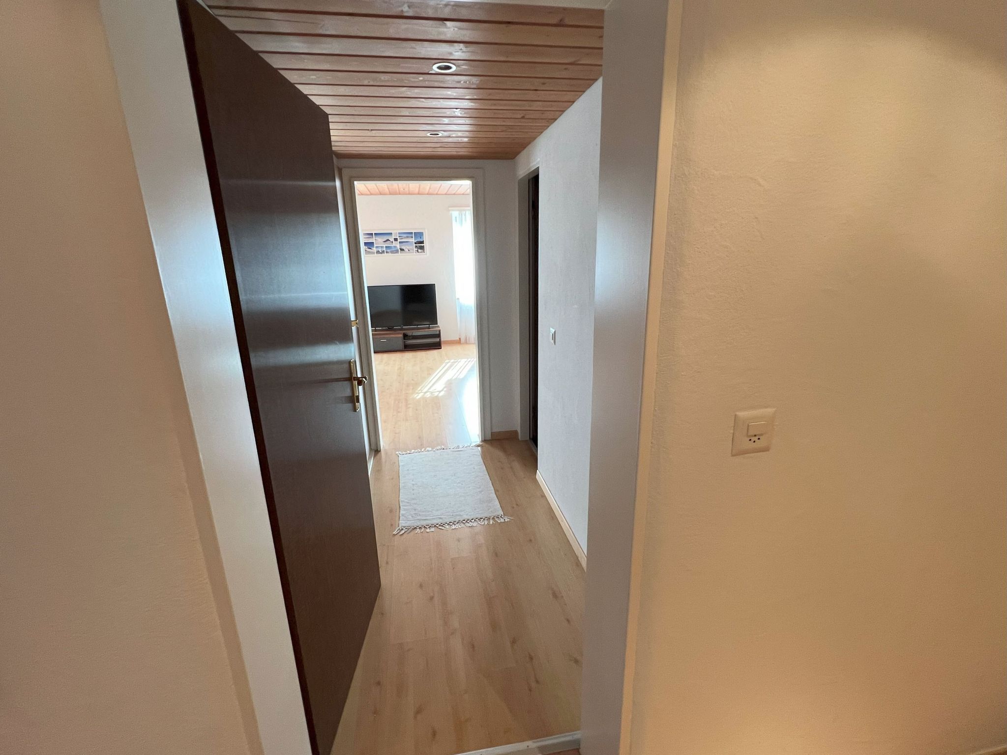 A narrow hallway with wooden flooring and a ceiling with exposed beams.