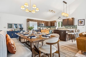 A modern kitchen with dark wooden cabinets, a central island with bar stools, and a dining area with a wooden table and chairs.