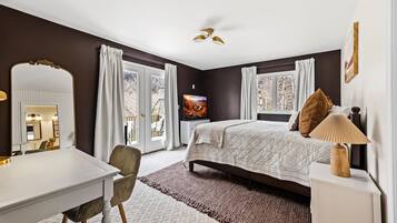 A bedroom with a bed, bedside table, lamp, and a large mirror.