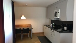 Een kleine keuken met een eethoek, een magnetron en een koffiezetapparaat.