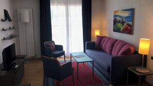 Een moderne hotelkamer met een bank, een kleine tafel, een televisie, een lamp en een schilderij aan de muur.