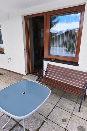 Un espace patio avec une table et un banc, une porte-fenêtre coulissante et une vue sur un paysage enneigé.