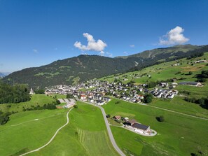 Un village avec des maisons, des routes et des champs verdoyants.