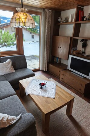 Un salon confortable avec un canapé, une table basse en bois, un téléviseur et une bibliothèque.
