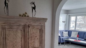 Et værelse med et stort træskab, en blå sofa og en buet døråbning til et andet rum.