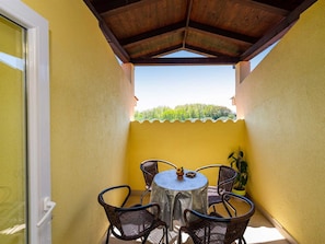 Un pequeño patio al aire libre con una mesa redonda y cuatro sillas, una planta en maceta y vistas a un paisaje verde.
