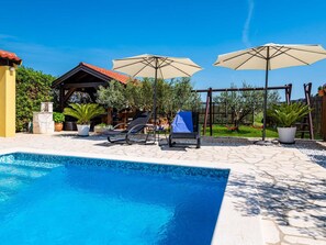 A swimming pool with lounge chairs and umbrellas, surrounded by a garden and a wooden pergola. - Apartment house Simoni with pool by Interhome (Privlaka)