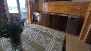 A kitchen with wooden cabinets, a built-in oven, a dishwasher, and a window providing natural light. - House Deša with amazing Old Town and sea view (Dubrovnik)
