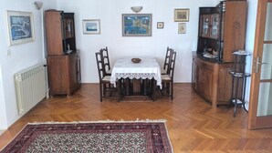 A dining area with a table, chairs, a patterned rug, and wall-mounted artwork. - House Deša with amazing Old Town and sea view (Dubrovnik)
