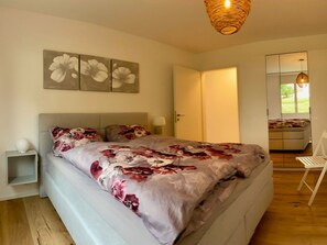 A bedroom with a bed, a nightstand, a chair, a wardrobe, and a hanging light fixture. - Casa Primavera B21, (Flims Dorf), by Interhome (Flims)