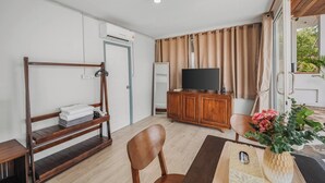 Ein Zimmer mit einem Etagenbett, einem Fernseher, einem Holzschrank, einem Sessel und einer Pflanze.