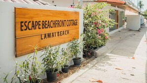 Ein Holzschild für Escape Beachfront Cottage am Strand von La Mata.