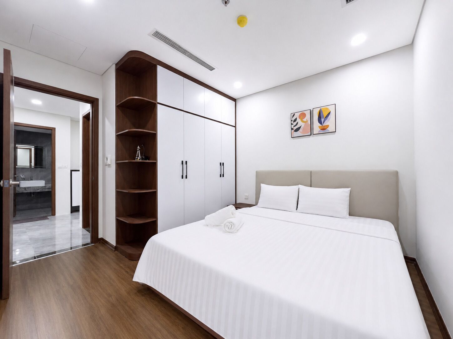 A modern bedroom with a bed, wardrobe, and a bathroom visible through an open door.